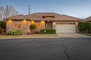 View of front of home featuring an attached garage, a tile roof, concrete driveway, and stucco siding