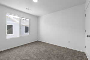 Carpeted empty room featuring baseboards and visible vents