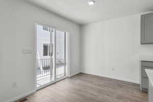 Unfurnished dining area featuring light wood-type flooring, visible vents, baseboards, and a textured ceiling