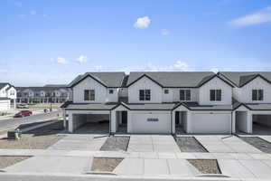 View of front of house with driveway, a garage, a residential view, roof with shingles, and board and batten siding