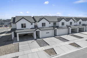 View of front of home featuring driveway, a residential view, roof with shingles, an attached garage, and board and batten siding