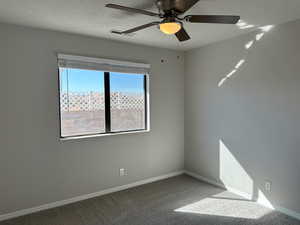 Carpeted spare room with a ceiling fan, baseboards, visible vents, and a textured ceiling