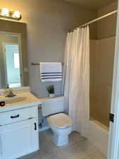 Bathroom with shower / tub combo with curtain, vanity, toilet, and tile patterned floors