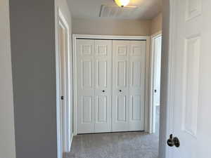 Hall featuring a textured ceiling, visible vents, and carpet flooring