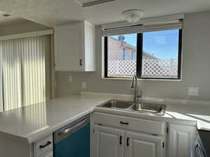 Kitchen with visible vents, dishwasher, a peninsula, white cabinetry, and a sink