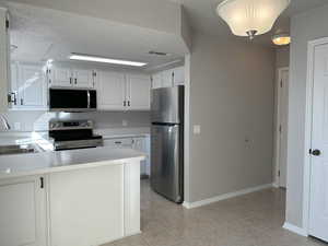 Kitchen featuring light countertops, visible vents, appliances with stainless steel finishes, a sink, and a textured ceiling