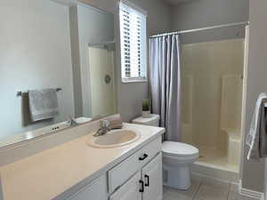 Bathroom with tile patterned flooring, toilet, a shower stall, and vanity