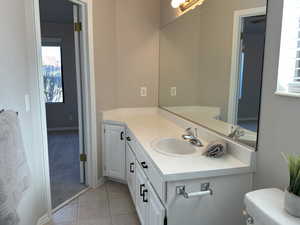 Half bathroom with toilet, tile patterned flooring, and vanity