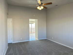 Carpeted empty room with visible vents, ceiling fan, and baseboards