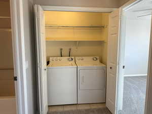 Laundry area featuring light tile patterned floors, laundry area, separate washer and dryer, and light colored carpet