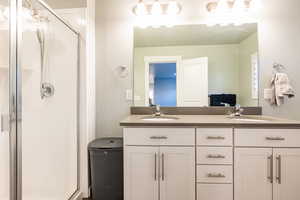 Full bath featuring double vanity, a shower stall, and a sink