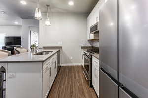 Kitchen with stainless steel appliances, a peninsula, a sink, white cabinetry, and a kitchen bar