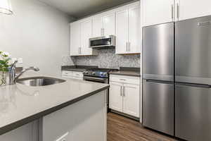 Kitchen featuring appliances with stainless steel finishes, dark countertops, a sink, and white cabinets