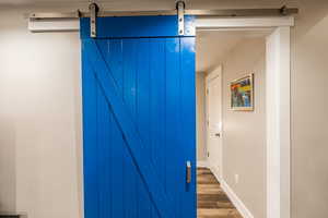 Hall featuring a barn door, dark wood-type flooring, and baseboards