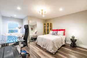 Bedroom with an inviting chandelier, visible vents, baseboards, and wood finished floors