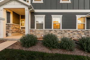 Property entrance featuring stone siding and board and batten siding