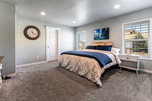 Bedroom featuring baseboards, dark colored carpet, a textured ceiling, and recessed lighting