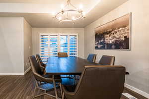 Dining space featuring dark wood-type flooring, a notable chandelier, a textured ceiling, and baseboards