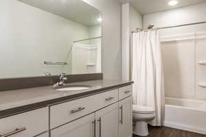 Full bath with toilet, recessed lighting, wood finished floors, vanity, and shower / bath combo with shower curtain