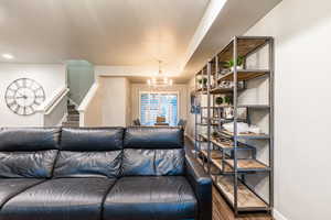 Living room featuring a textured ceiling, stairs, baseboards, and a notable chandelier