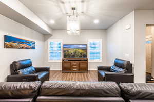 Living area featuring light wood-style floors, baseboards, a chandelier, and recessed lighting