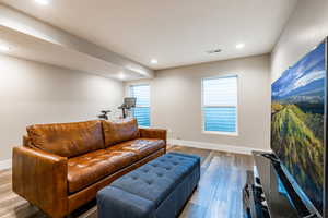 Living area featuring a textured ceiling, baseboards, wood finished floors, and recessed lighting