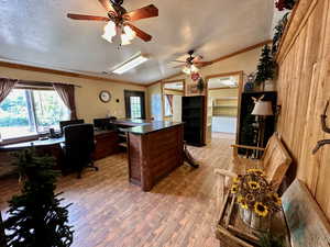 Office area featuring lofted ceiling, a textured ceiling, a ceiling fan, light wood-style floors, and ornamental molding