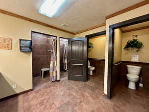 Bathroom with visible vents, a textured ceiling, wainscoting, and toilet
