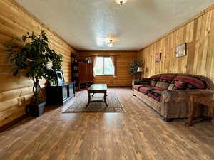 Living area with rustic walls, a textured ceiling, and wood finished floors