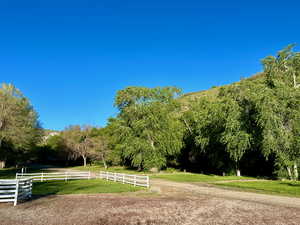 View of community with fence, a lawn, and a rural view