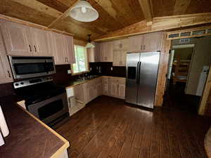 Kitchen featuring lofted ceiling, dark wood-type flooring, a sink, white cabinets, and appliances with stainless steel finishes