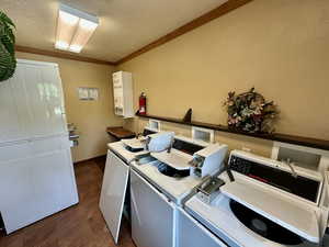 Shared laundry area with ornamental molding, washer and dryer, a textured ceiling, and dark tile patterned floors