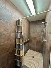 Full bathroom with a tile shower and a textured ceiling