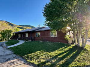 Rear view of house featuring metal roof, a lawn, a mountain view, and faux log siding