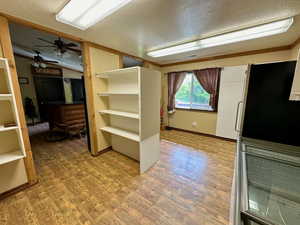 Interior space featuring light wood-type flooring, lofted ceiling, freestanding refrigerator, and a textured ceiling
