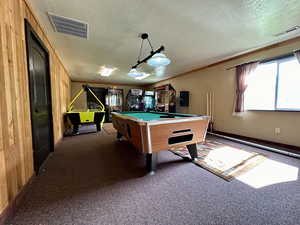Recreation room featuring a textured ceiling, dark carpet, billiards, and visible vents