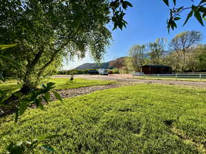 View of yard featuring a rural view, fence, a mountain view, and an outbuilding