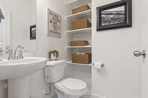 Bathroom with toilet, marble finish floor, baseboards, and a sink