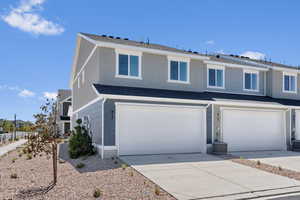 View of front of property with concrete driveway, central AC unit, an attached garage, and a shingled roof