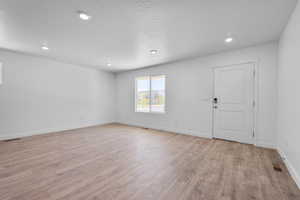 Spare room with a textured ceiling, baseboards, visible vents, and light wood-style floors