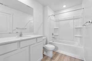 Full bath featuring shower / tub combination, toilet, wood finished floors, vanity, and visible vents