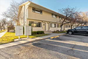 Townhome / multi-family property with uncovered parking and brick siding