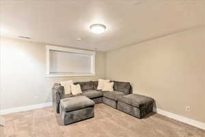 Carpeted living area featuring visible vents and baseboards