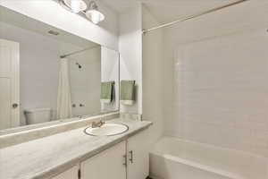 Full bath featuring toilet, visible vents, shower / bath combo with shower curtain, and vanity