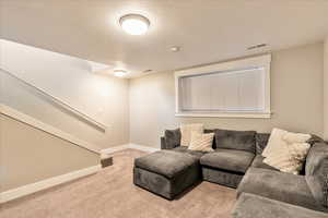 Living area featuring light carpet, a textured ceiling, visible vents, and baseboards