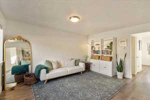 Living area with a textured ceiling, visible vents, and wood finished floors