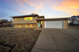 Split level home featuring an attached garage, concrete driveway, and brick siding