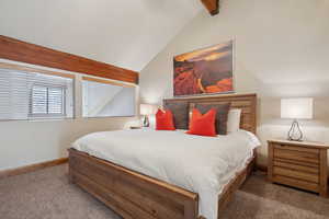 Carpeted bedroom with vaulted ceiling with beams and baseboards