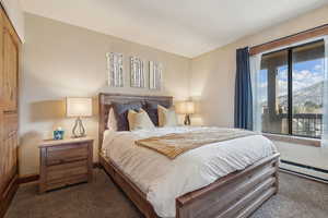 Bedroom with dark colored carpet, baseboard heating, and a mountain view