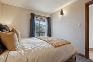 Bedroom featuring access to exterior, wood finished floors, and a textured wall